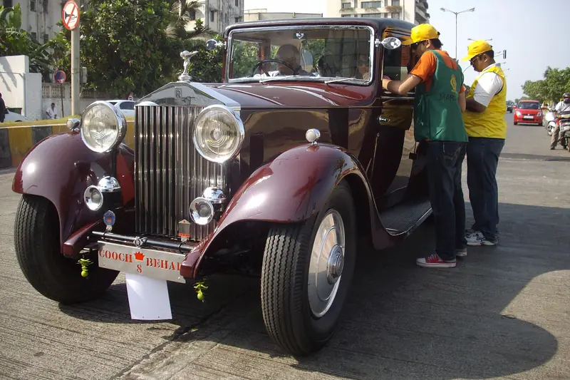 Maroon vintage Rolls-Royce with spoked wheels at a classic car rally